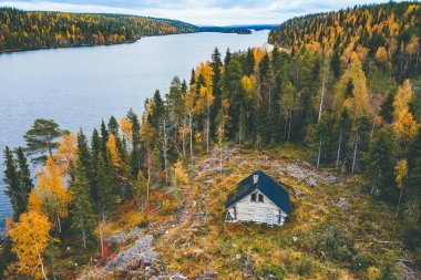 Aerial view of the log sauna cabin near blue river in colourful autumn forest in Finland Lapland