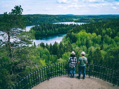 A young couple from back on the observation deck among blue lakes and green forests in summer Finland, Hameenlinna.