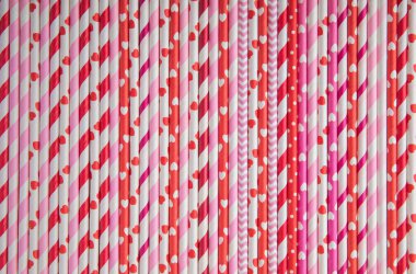 Drinking straws for Valentine's day. Red, pink and white party paper drinking straws on pink background, top view.