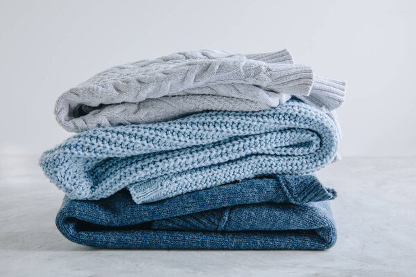 Sweaters. Blue knitted sweaters stacked on gray background.