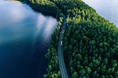 Yazın Finlandiya 'da yeşil ormanlık ve mavi göllerdeki yol manzarası