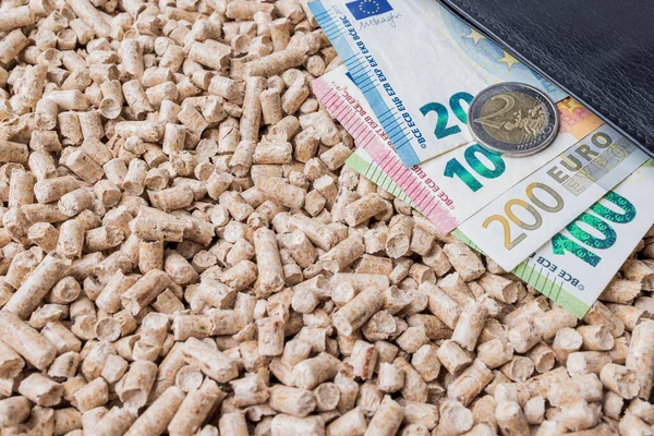 stock image Wooden pellets background with euro banknotes. Biofuel, ecological heating, alternative energy concepts. Top view, copy space.