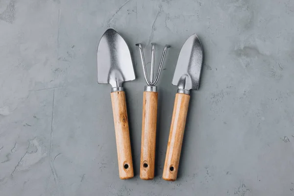 Garden tools. Wooden metal garden tools set on gray concrete stone background. Top view