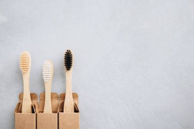 Bambu diş fırçaları. Gri taştan arka planda çevre dostu bambu diş fırçaları, fotokopi alanı olan üst manzara. Biyolojik çözünebilir ahşap ağız hijyen aksesuarları. Sıfır atık, plastiksiz, sürdürülebilir yaşam tarzı konsepti