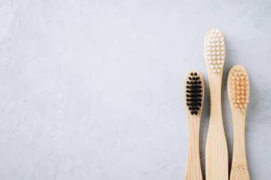Bambu diş fırçaları. Gri taştan arka planda çevre dostu bambu diş fırçaları, fotokopi alanı olan üst manzara. Biyolojik çözünebilir ahşap ağız hijyen aksesuarları. Sıfır atık, plastiksiz, sürdürülebilir yaşam tarzı konsepti