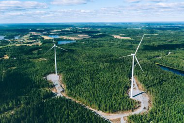 Değirmenler, rüzgar türbinleri. Finlandiya 'daki yeşil yaz ormanlarındaki yel değirmenlerinin havadan görünüşü. Temiz ve yenilenebilir enerjili elektrik gücü için rüzgar türbinleri