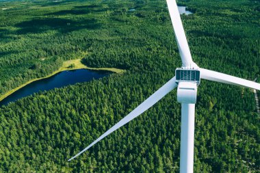 Değirmenler, rüzgar türbinleri. Finlandiya 'daki yeşil yaz ormanlarındaki yel değirmenlerinin havadan görünüşü. Temiz ve yenilenebilir enerjili elektrik gücü için rüzgar türbinleri