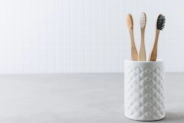 Eco toothbrushes. Bamboo toothbrushes cup on gray stone background, copy space. Minimal bath background