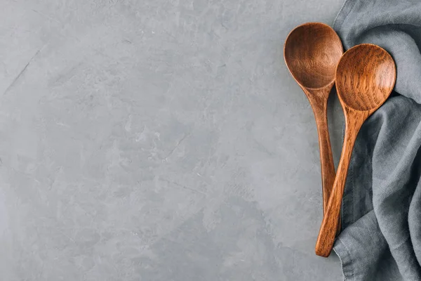 Wooden spoons. Two wooden spoons with napkin on gray concrete stone background, kitchen concept. Top view, copy space.