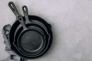 Boş tavalar. Gri taş arka planda peçeteli demir tavalar, üst manzara, kopyalama alanı. Mutfak gereçleri arka plan kavramı.