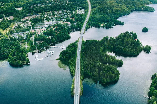 stock image Aerial view of road bridge with cars between green forests and blue lakes in rural Finland. Beautiful summer landscape