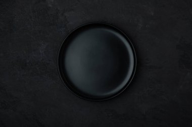 Boş tabak. Koyu siyah seramik, siyah taşlı arka planda boş bir tabak. Üst görünüm, alanı kopyala