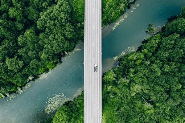芬兰蓝色河流与绿色夏季森林上有车的桥道空中景观 免版税图库照片