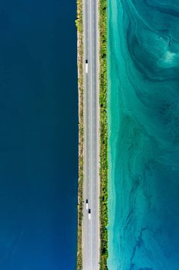 Mavi ve turkuaz su nehir okyanusu arasında asfalt köprü yolunun hava manzarası. İnanılmaz yaz manzarası..