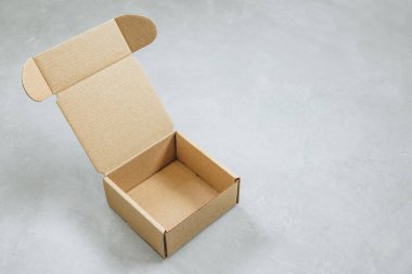 Karton kutu. Kahverengi karton kutu. Gri arka planda kahverengi karton kutu, içi boş. Hediye ve teslimat için kare karton kutu