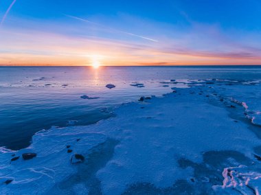 Buzlu ve günbatımında gökyüzü olan mavi deniz suyunun hava aracı görüntüsü. Finlandiya 'da güzel kış manzarası