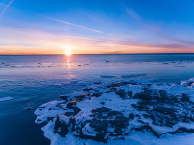 Buzlu ve günbatımında gökyüzü olan mavi deniz suyunun hava aracı görüntüsü. Finlandiya 'da güzel kış manzarası
