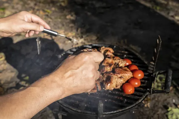 man cooking  meat on grill in the garden.