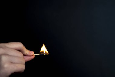 Elinde yanan kibrit tutan adam siyah arka planda..