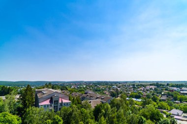 Mavi gökyüzünün altındaki küçük şehir ve yeşil ağaçların havadan görünüşü