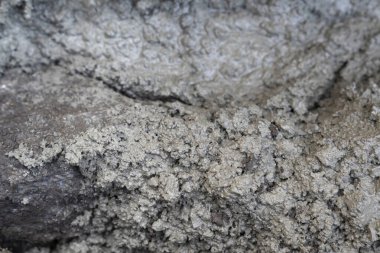 Sert desenli ve küçük taşlı ıslak gri çamur. Doğal çamurlu yüzeyin makro görüntüsü.