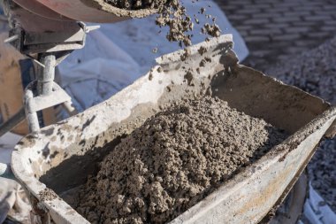 İnşaat alanında içinde ıslak çimento olan kırmızı beton karıştırıcı. Kurumuş çimentoyla kaplanmış dönen davulun yakın plan çekimi. Endüstriyel inşaat ve inşaat süreci kavramı.