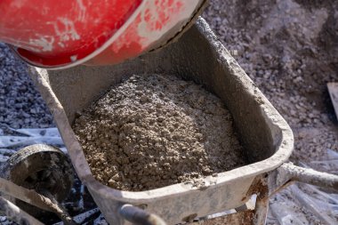İnşaat alanında içinde ıslak çimento olan kırmızı beton karıştırıcı. Kurumuş çimentoyla kaplanmış dönen davulun yakın plan çekimi. Endüstriyel inşaat ve inşaat süreci kavramı.