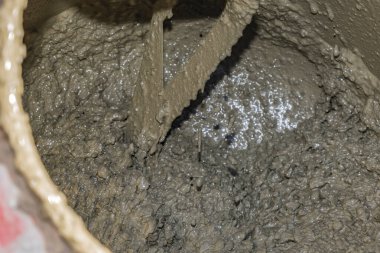 İnşaat alanında içinde ıslak çimento olan kırmızı beton karıştırıcı. Kurumuş çimentoyla kaplanmış dönen davulun yakın plan çekimi. Endüstriyel inşaat ve inşaat süreci kavramı.