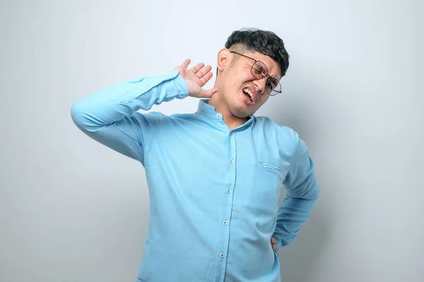 stock image Young handsome asian man wearing casual shirt standing over white background stretching back, tired and relaxed, sleepy and yawning for early morning