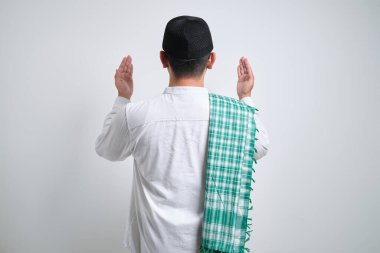 Genç Asyalı Müslüman adam elini kaldırdı ve beyaz arka planda tek başına dua etti.