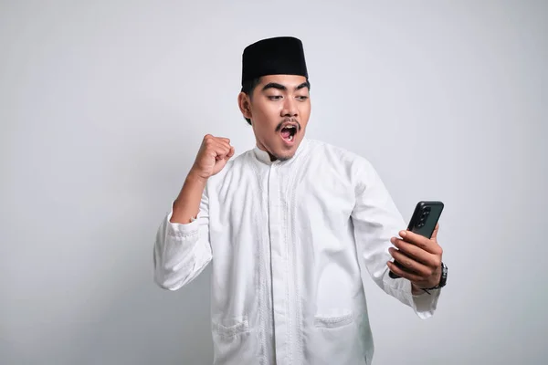Asiatisk Muslim Man Vita Kläder Innehav Smartphone Gör Vinnande Gest — Stockfoto