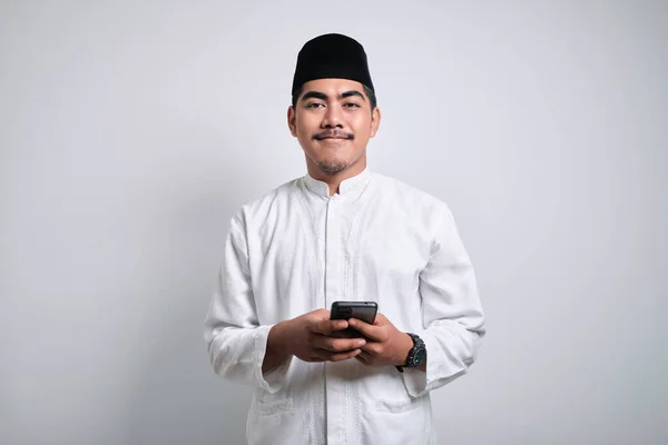 Szczęśliwy Muzułmanin Azjatycki Białych Ubraniach Trzyma Wskazuje Komórkę Białym Tle — Zdjęcie stockowe