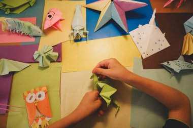 İlkokul çocuğu kendi yaptığı origamiyle oynuyor.