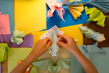 İlkokul çocuğu kendi yaptığı origamiyle oynuyor.