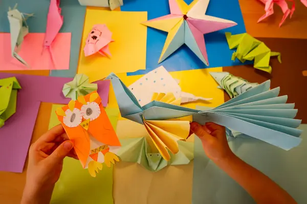 İlkokul çocuğu kendi yaptığı origamiyle oynuyor.
