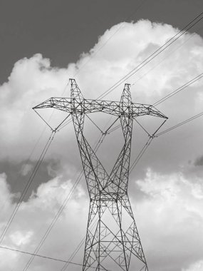 Bulutlu yaz gününde yüksek voltajlı elektrik direği manzarası