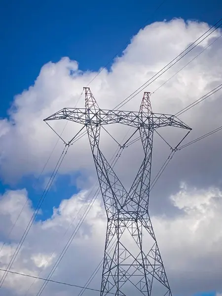 Bulutlu yaz gününde yüksek voltajlı elektrik direği manzarası