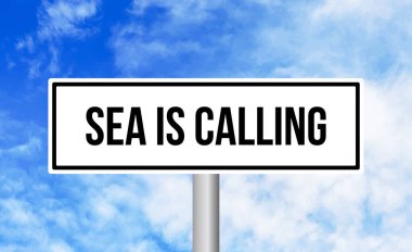 Deniz, mavi gökyüzü arka planında yol tabelasını çağırıyor