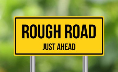 Bulanık zeminde Rough Road tabelası var.