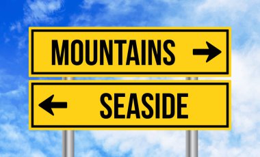 Mavi arka planda dağlar ya da deniz kenarındaki yol tabelası