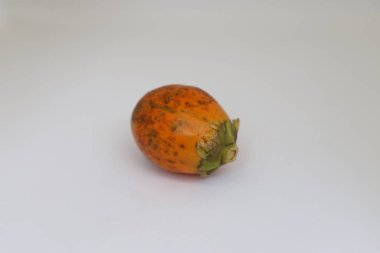 Canlı turuncu tonlar ve koyu benekli noktalar sergileyen tek bir desenli betel fındık doğal detaylarını ve gövdesini gösteren el değmemiş beyaz bir yüzey üzerindedir..