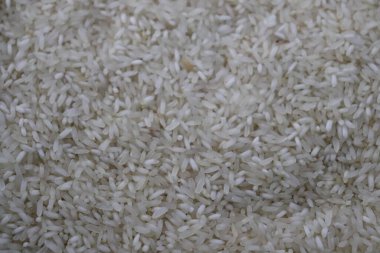 Ayrıntılı yakın plan çekimleri, gıda ve tarımla ilgili kullanımlar için dokusal bir zemin oluşturan büyük bir yığın çiğ, kuru pirinç gösteriyor..