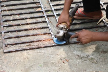 İspanyol inşaat işçisi metal ızgarayı elektrikli öğütücüyle öğütüyor ve bir sürü kıvılcım yaratıyor. Güvenli olmayan uygulama, güvenlik kavramı.