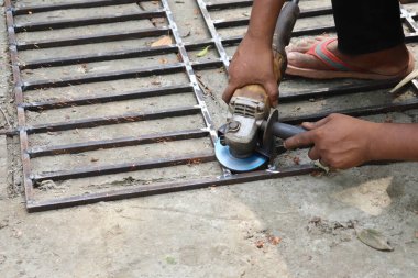 Metal bir çubuğu öğüten bir adamın yakın plan çekimi kıvılcımlar yaratıyor. Güvenlik önlemleri mevcut değil. Sıcak mavi elektrikli bir aletle çelik işçiliği.