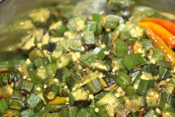 Dilimlenmiş ve baharatlı kızarmış bamyanın yakın görüntüsü. Kırmızı biberle karıştırılmış yeşil bamya görsel olarak çekici bir yemek olur..