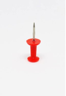 Keskin metal bir iğnenin olduğu, el değmemiş beyaz bir arka plan üzerine kurulmuş, tek ve canlı kırmızı bir itme iğnesinin detaylı bir çekimi. Stüdyo çekimi temiz ve net bir görüntü sunar.