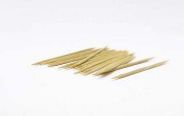 Yakın çekim stüdyo çekimlerinde, temiz, parlak beyaz bir yüzey üzerine dizilmiş düz, doğal ahşap kürdan yığını yer alır..