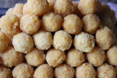 Yüksek açılı yakın çekim sergileniyor. Yuvarlak, sarı Besan Laddu, popüler Hint tatlısı, kumlu dokusu ve ince şeker kaplamalı..