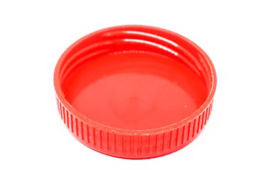 Tepeden çekimde belirgin tırtıklı desenli canlı bir kırmızı plastik şişe kapağı var. Beyaz bir zemin üzerine kurulmuş ve detaylarını vurguluyor..