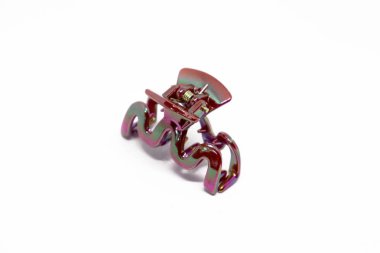 Yakından çekilen bu görüntüde yay ve yuvarlak kenarlı kenarlı parlak beyaz arka planda bulunan yanardöner metal bir saç pençe var..